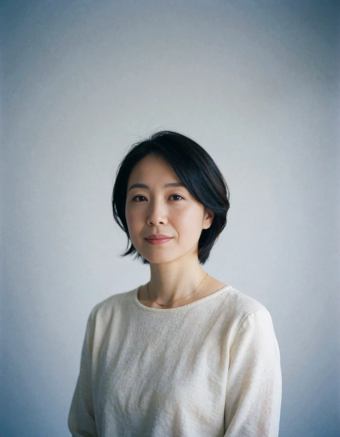 Japanese member in an ivory top photographed against a plain pale grey studio backdrop