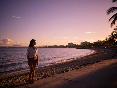 Filipina woman standing on a seaside promenade in Manila at sunset with the bay stretching behind her